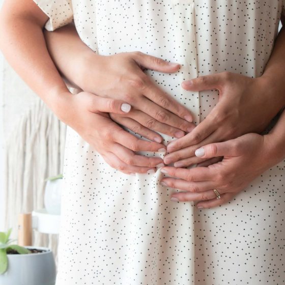 Woman and man's hands holding a pregnant woman's belly