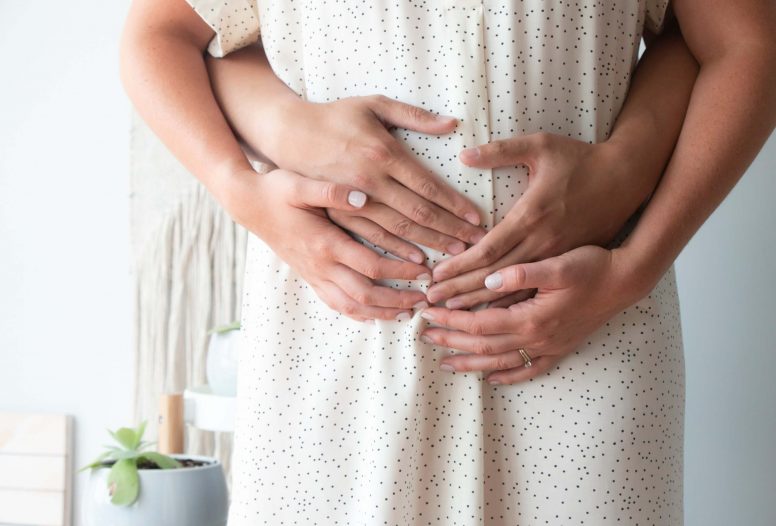 Woman and man's hands holding a pregnant woman's belly