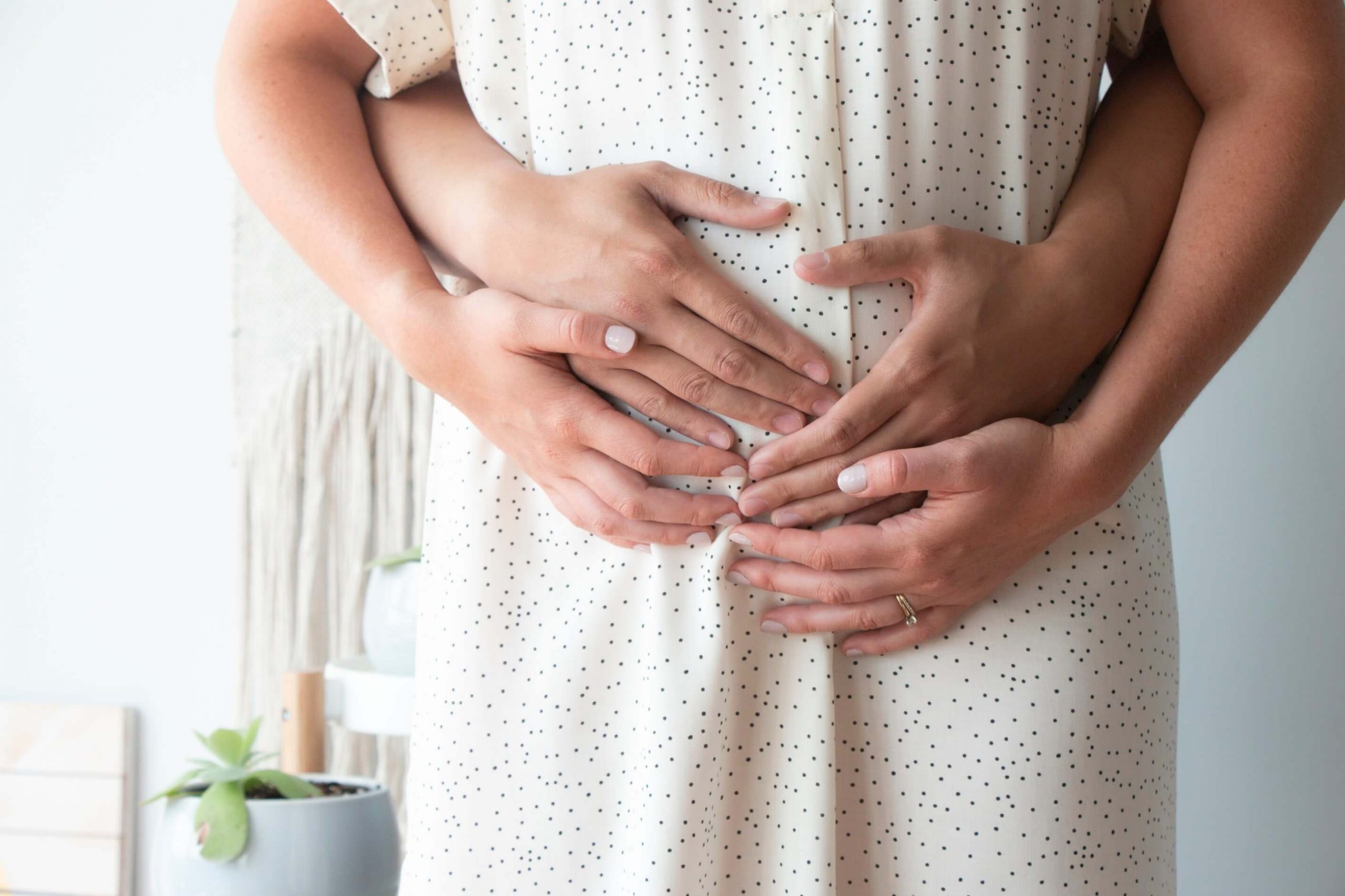 Woman and man's hands holding a pregnant woman's belly