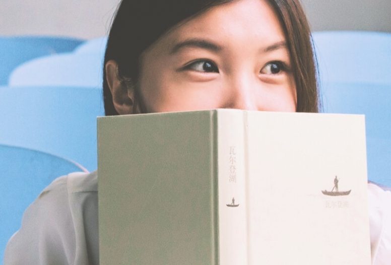 Woman peering over the top of book