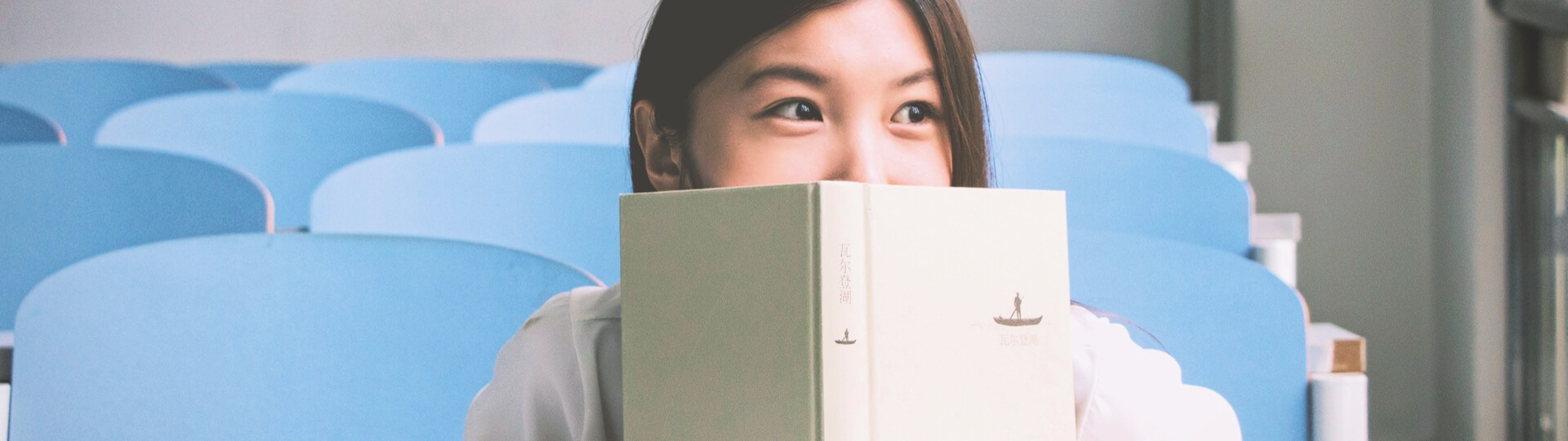 Woman peering over the top of book