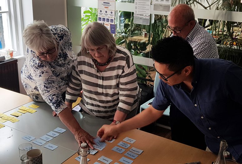 Group of people in UX workshop looking at cards on table