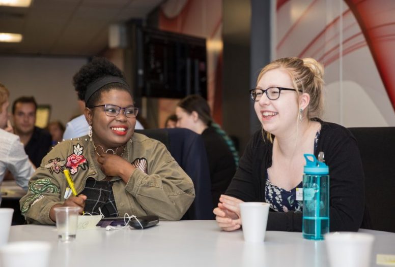 Two woman wearing glasses having drink together