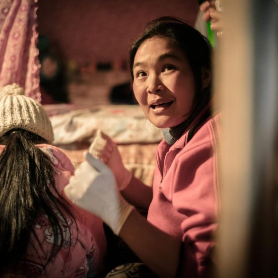 An HPA health worker with rubber gloves on helping another woman