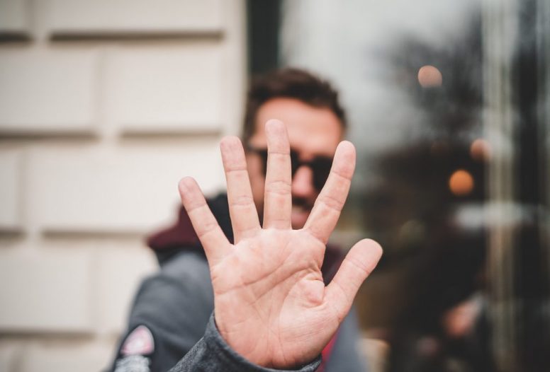 Man putting palm of hand up to camera