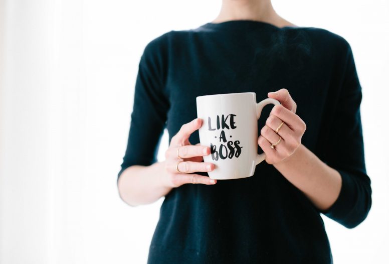 Woman in black holding a mug which reads like a boss