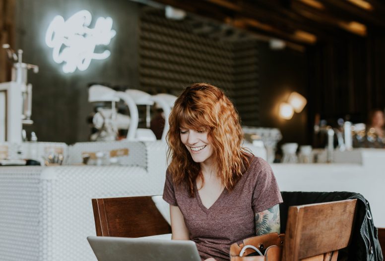 tattooed woman smiling at her laptop