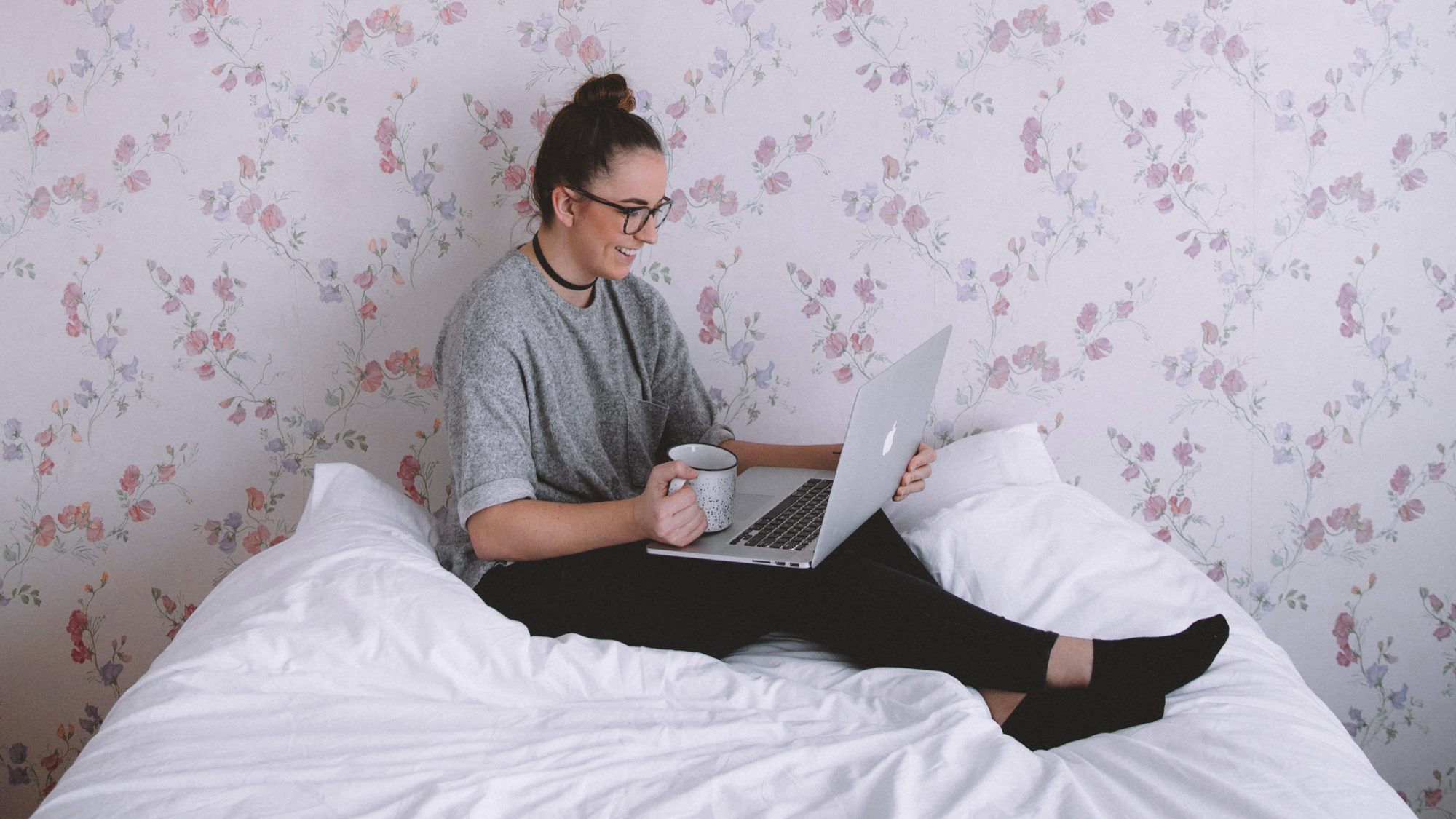 Woman working on her laptop from her bed at home