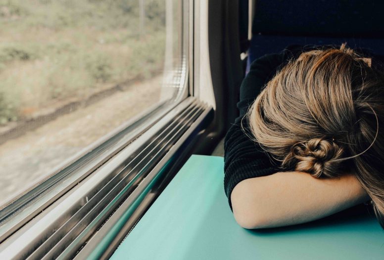 Woman with her head on the table asleep on a train