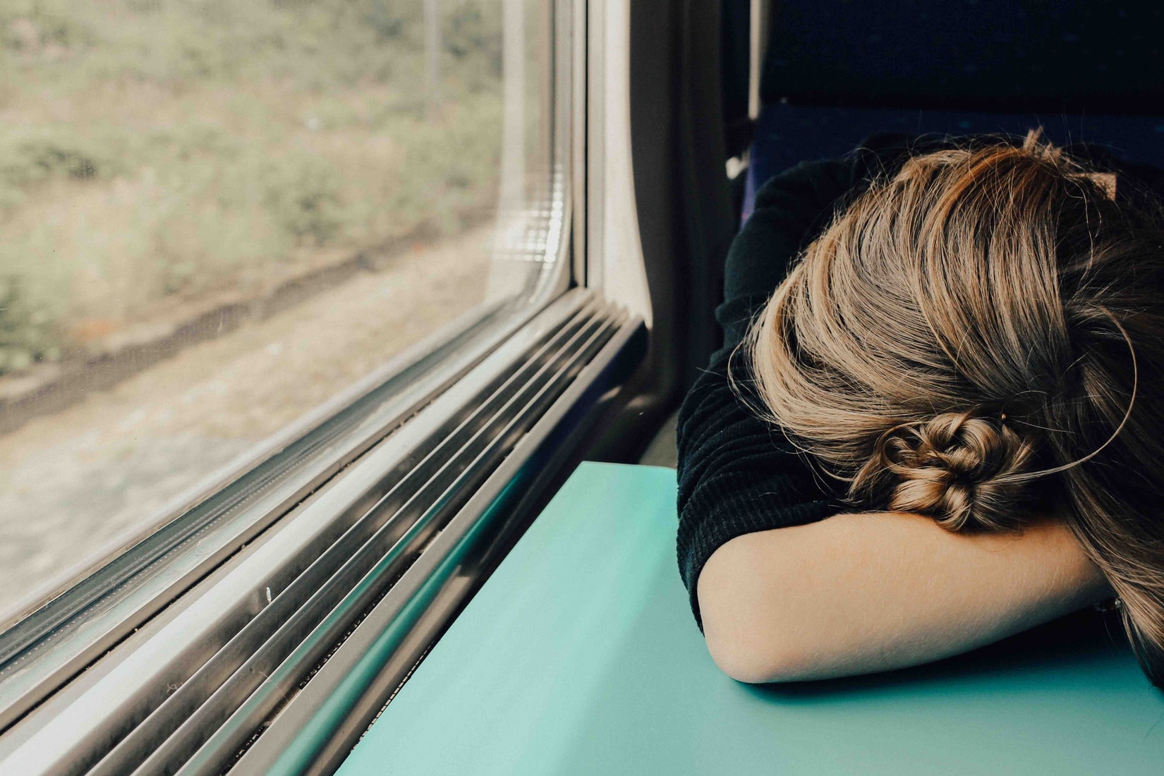 Woman with her head on the table asleep on a train