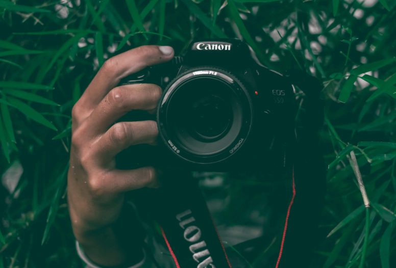 A man's hand holding a DSLR camera